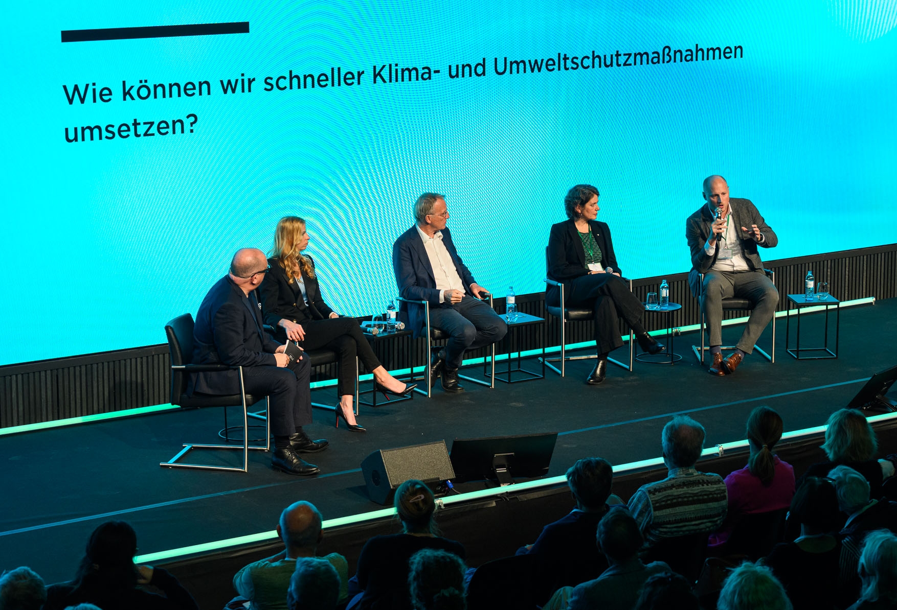 Bühne mit der Frage im Hintergrund Wie können wir schneller Klima- und Umweltschutzmaßnahmen umsetzten auf  dem Kongress Zeit Wissen 2024