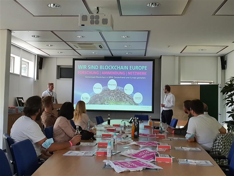 Das Bild zeigt einen Workshop, in dem sich die Teilnehmenden mit Blockchain-Geschäftsmodellen auseinandersetzen. In einer dynamischen Atmosphäre werden innovative Strategien diskutiert, die neue Marktchancen eröffnen. Notizen, Diagramme oder digitale Präsentationen unterstützen den kreativen Austausch und die Entwicklung zukunftsweisender Lösungen.