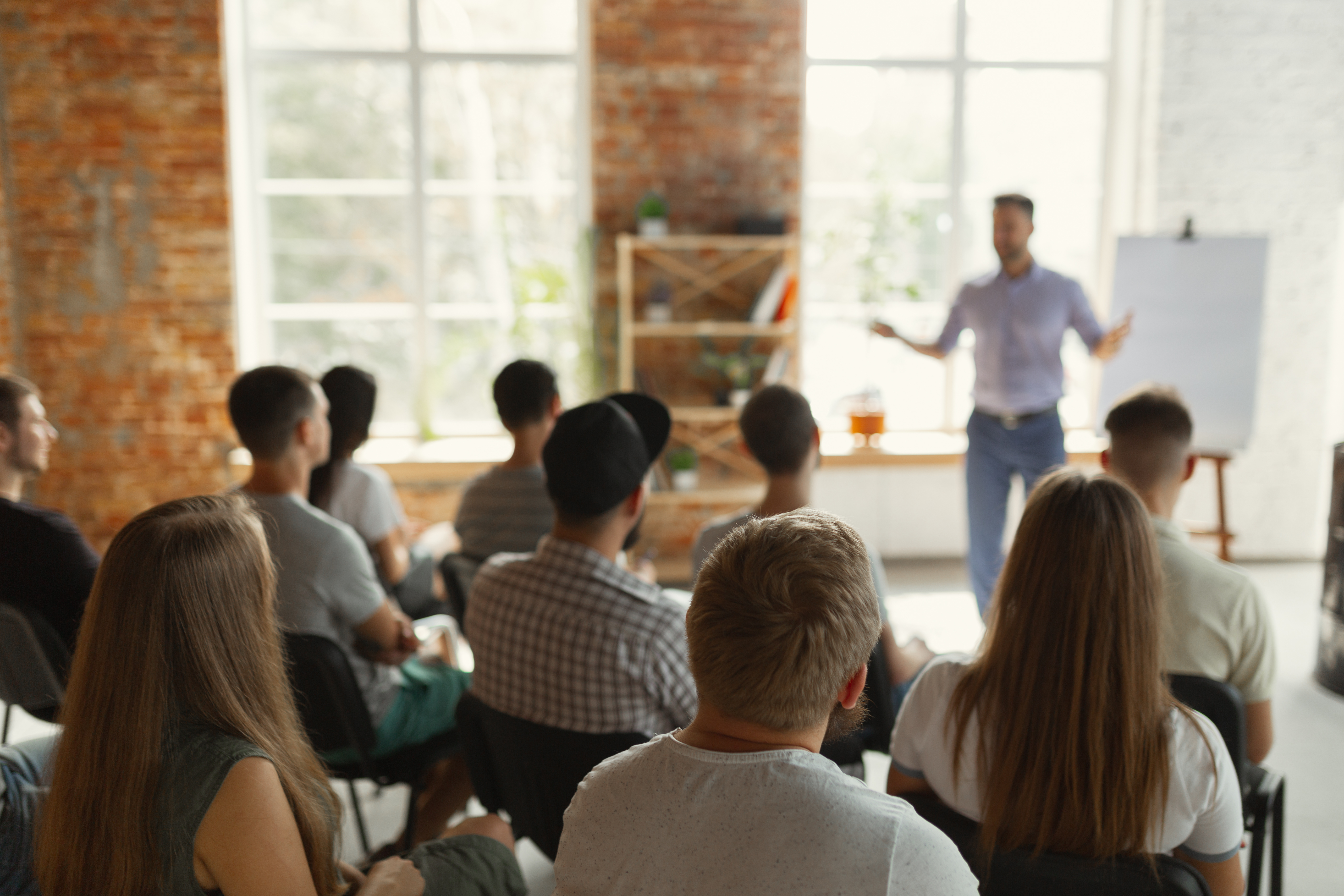 Das Bild zeigt einen Workshop, bei dem ein Mann vorne steht und den anderen etwas erklärt. Die Teilnehmenden hören aufmerksam zu und tauschen sich aus, während der Fokus auf nachhaltigen Geschäftsmodellen liegt.