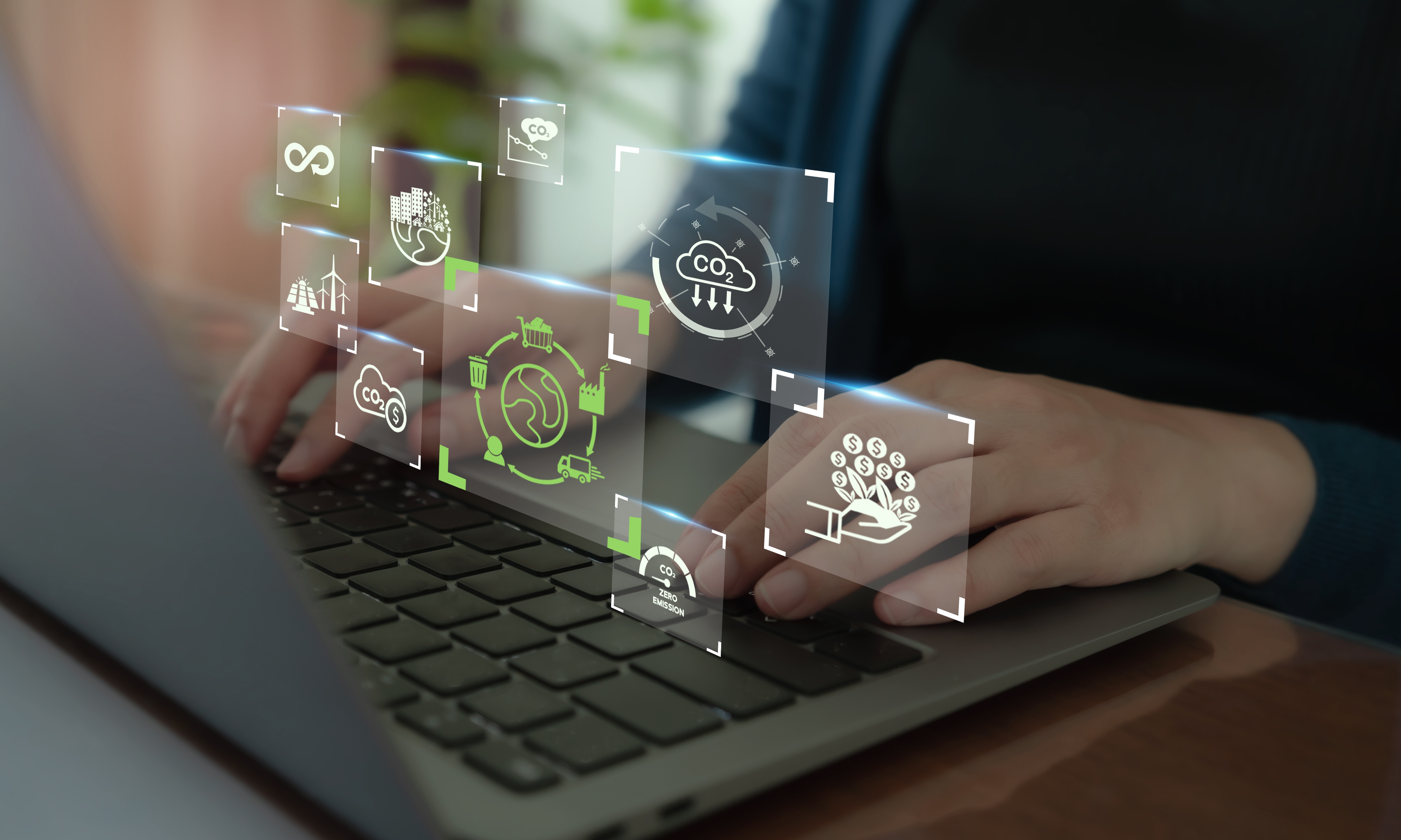 Das Bild zeigt eine Person, die an einem Laptop arbeitet, während digitale Symbole für ökologische und ökonomische Bewertungen sichtbar sind. Diese Symbole verdeutlichen die Verbindung zwischen Nachhaltigkeit, Wirtschaft und Umwelt.