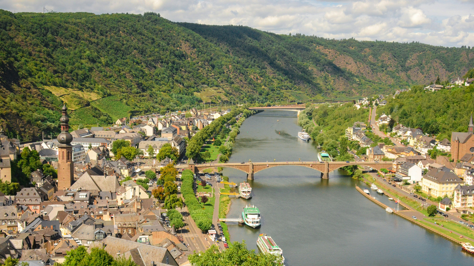 Foto der Mosel, die in einem Tal durch eine kleine, deutsche Stadt fließt.
