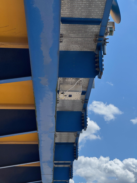 Nahaufnahme des robusten LIDAR-Sensorgehäuses am blauen Portalkran-Tragwerk: Die Box erfasst Containerpositionen millimetergenau für schnelleren Umschlag.