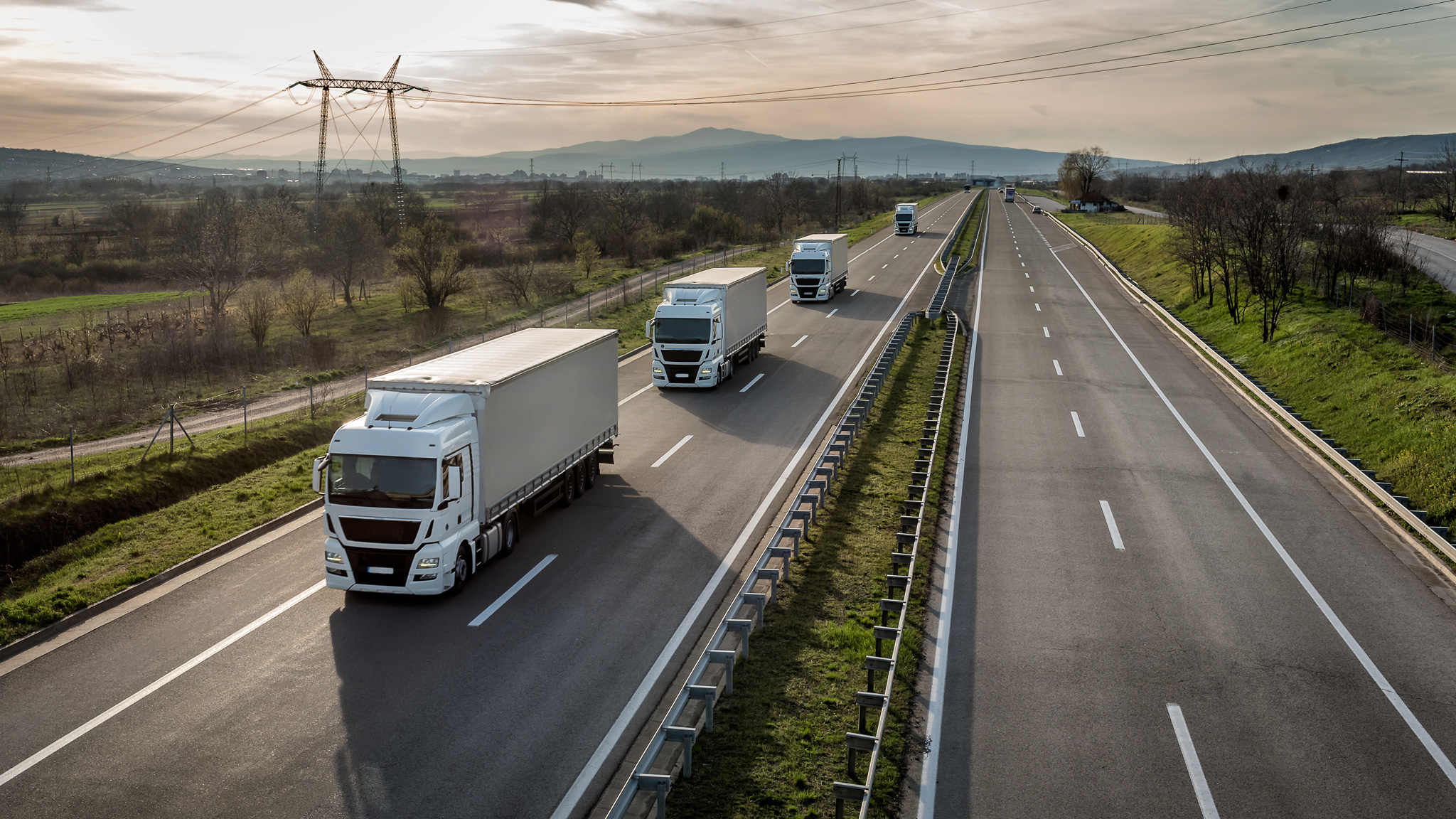 Vier Lkws fahren hintereinander eine Autobahn entlang.