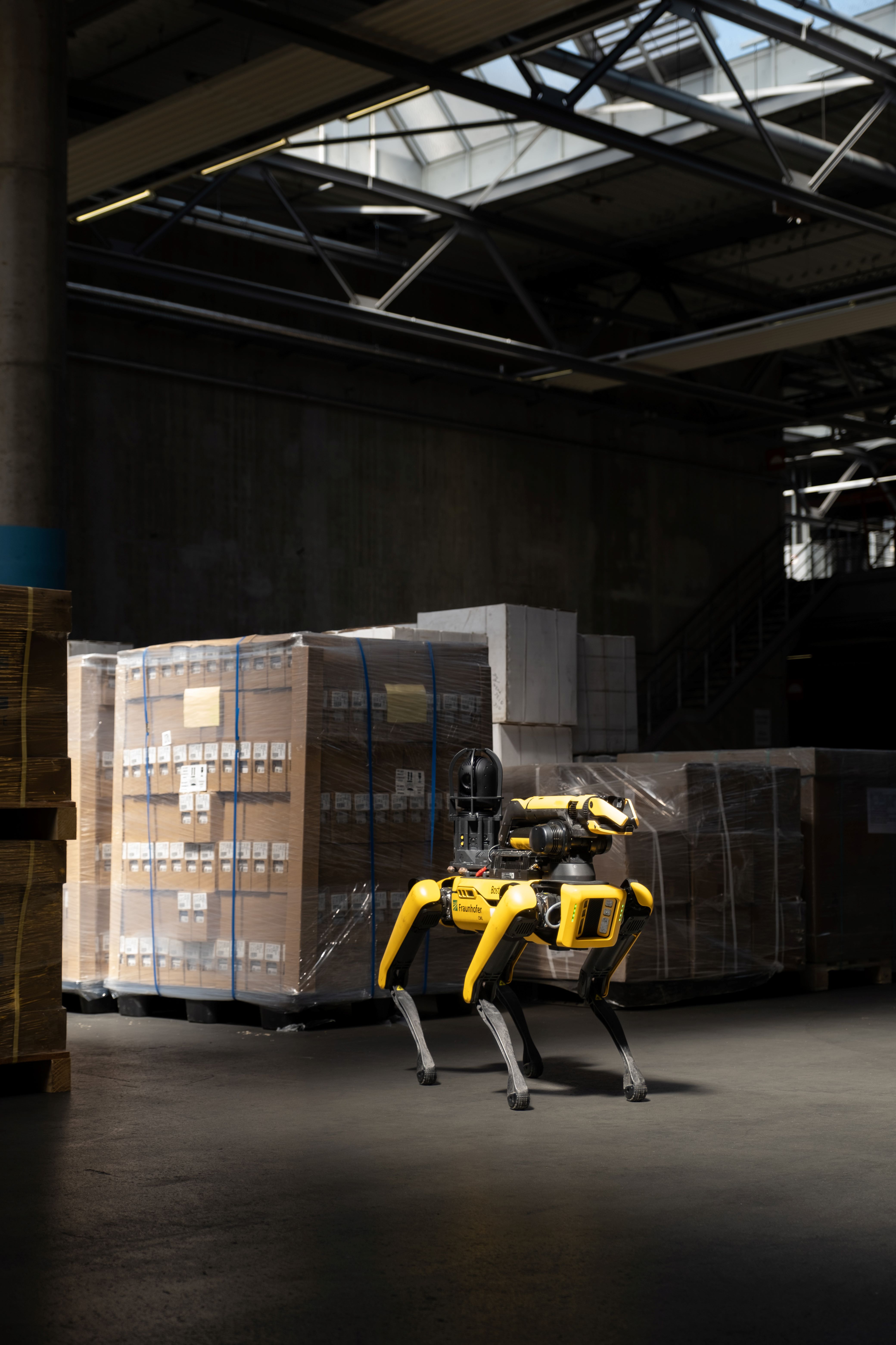 Roboterhund Spot steht in einer abgedunkelten Lagerhalle.