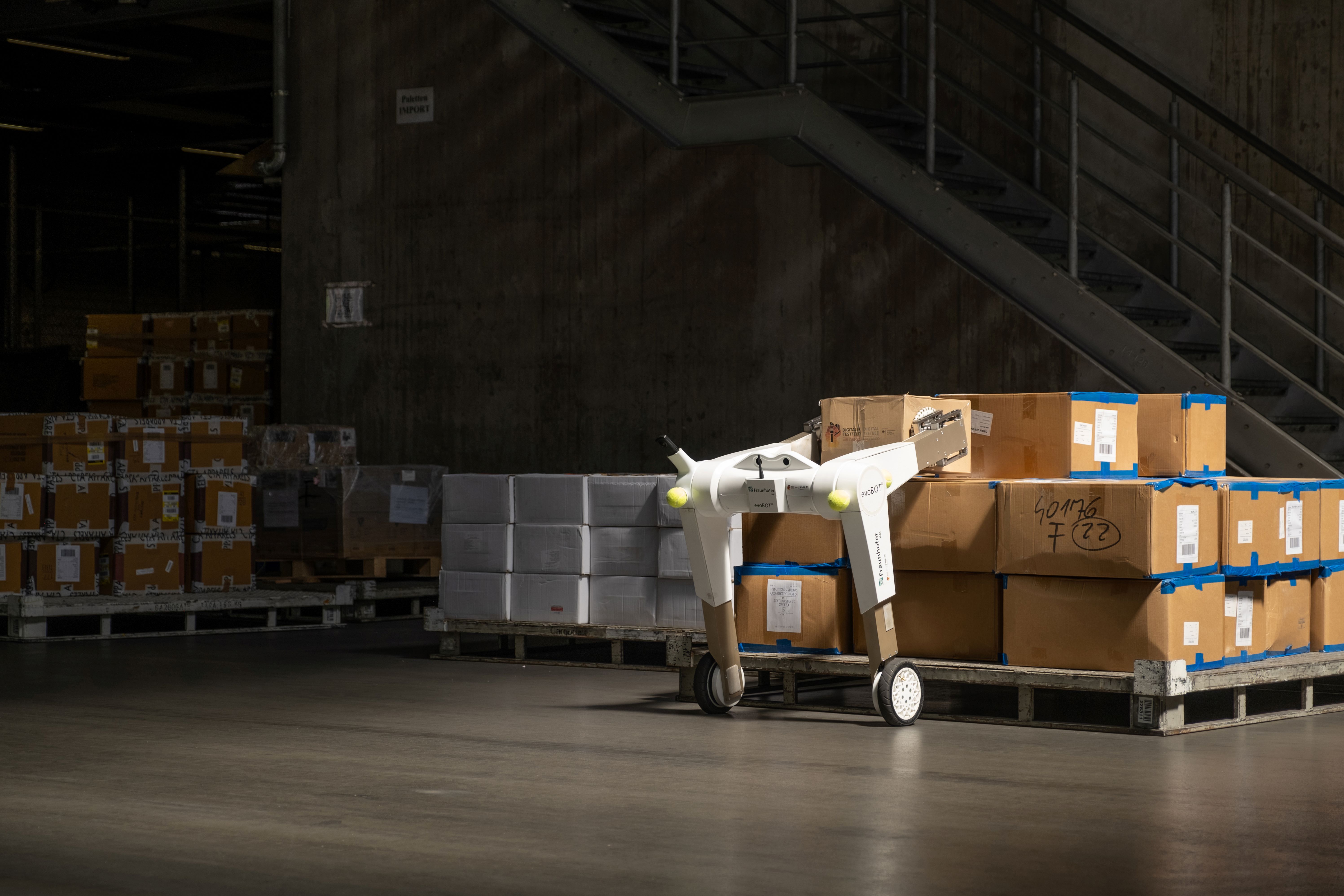 Der Roboter evoBOT hebt ein Paket von einem Stapel an.