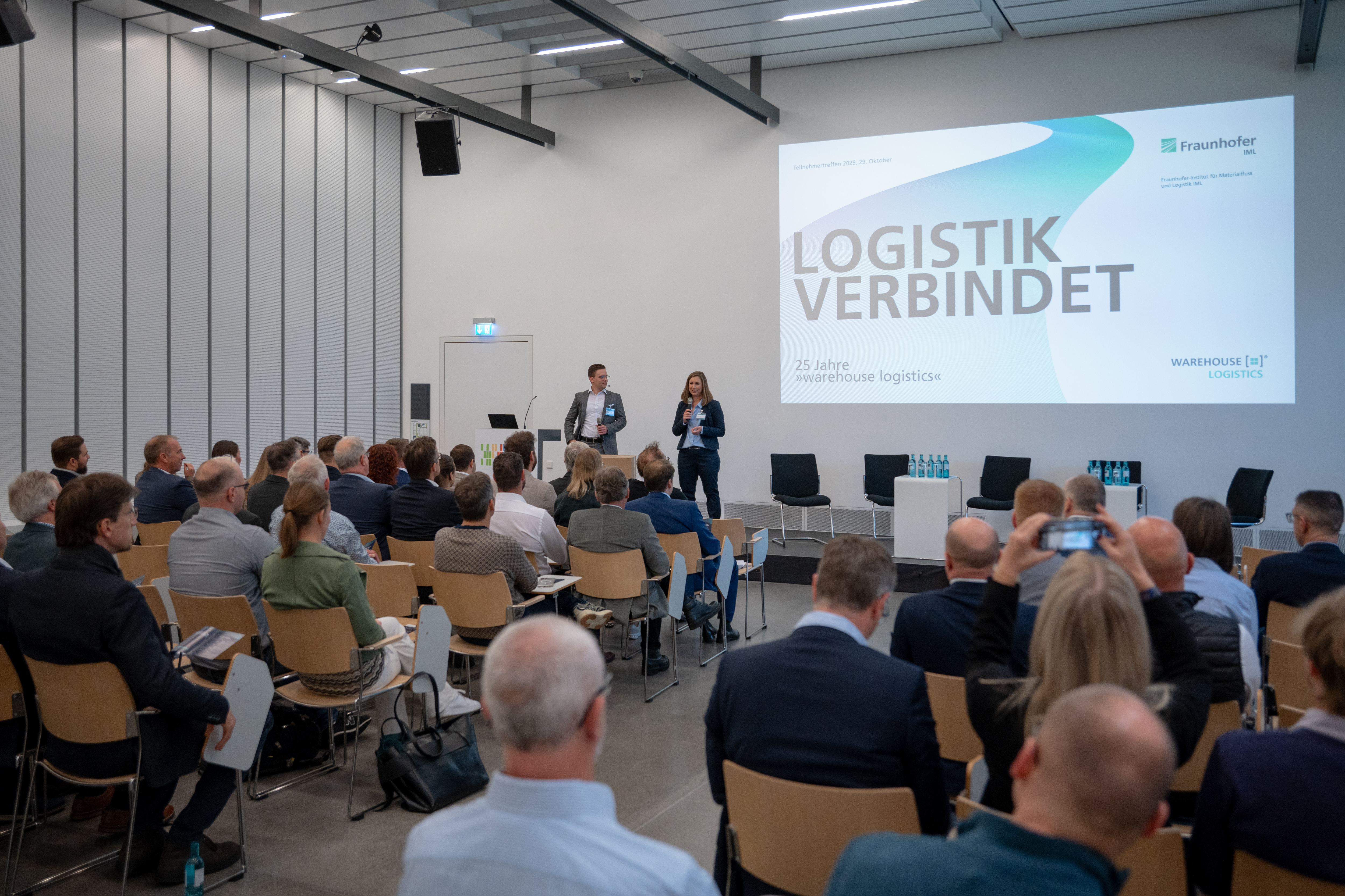 Eröffnung im Hörsaal am Logistik‑Campus: Start des Jubiläums „Logistik verbindet – 25 Jahre warehouse logistics“ mit rund 80 Teilnehmenden; Austausch und Führung durch Forschungshallen.