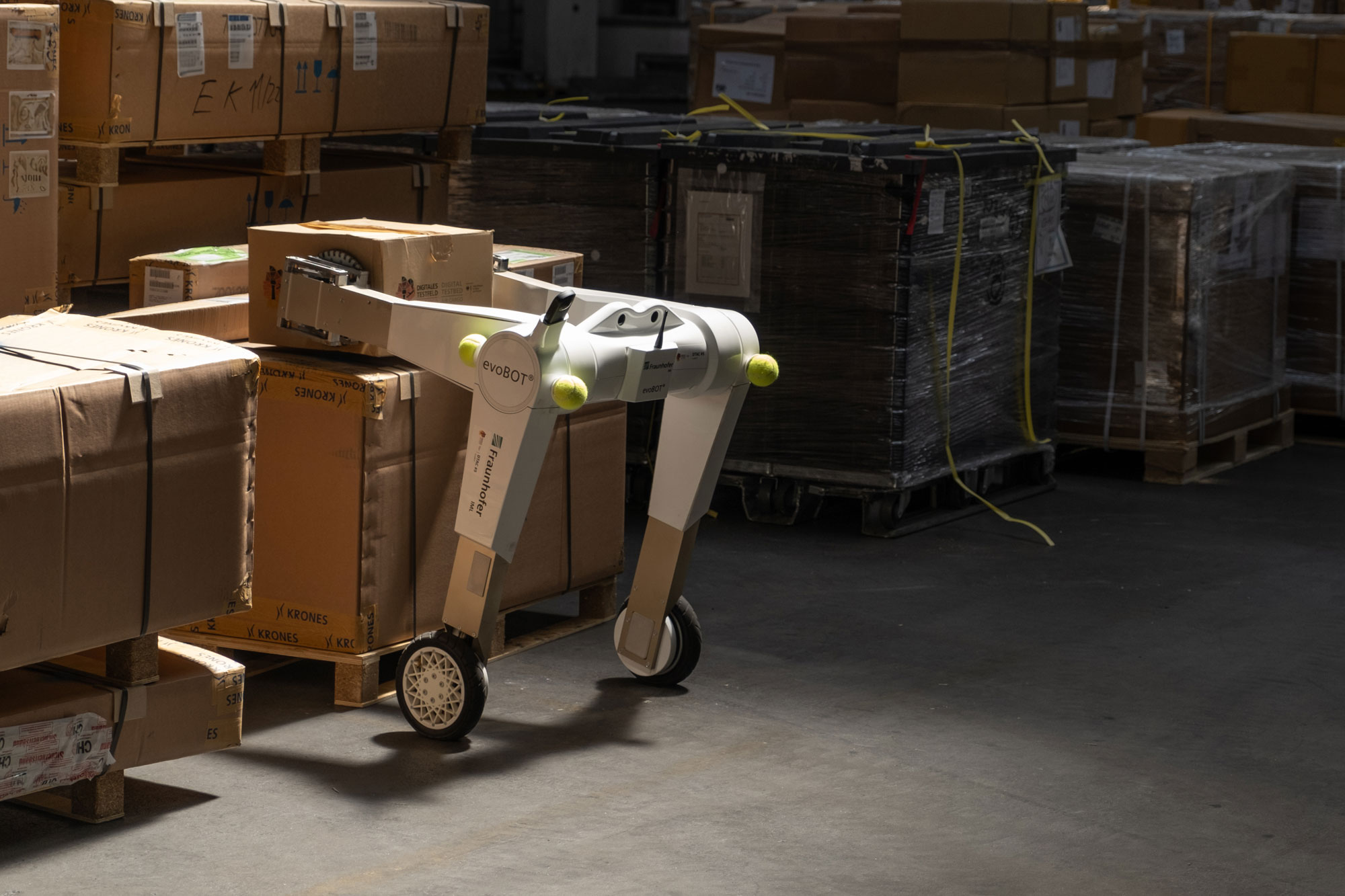 evoBot, konstruiert vom Fraunhofer IML, hebt Paket von Palette bei der Luftfrachtabfertigung am Flughafen München während der Demonstration des Forschungsprojekts DTAC.
