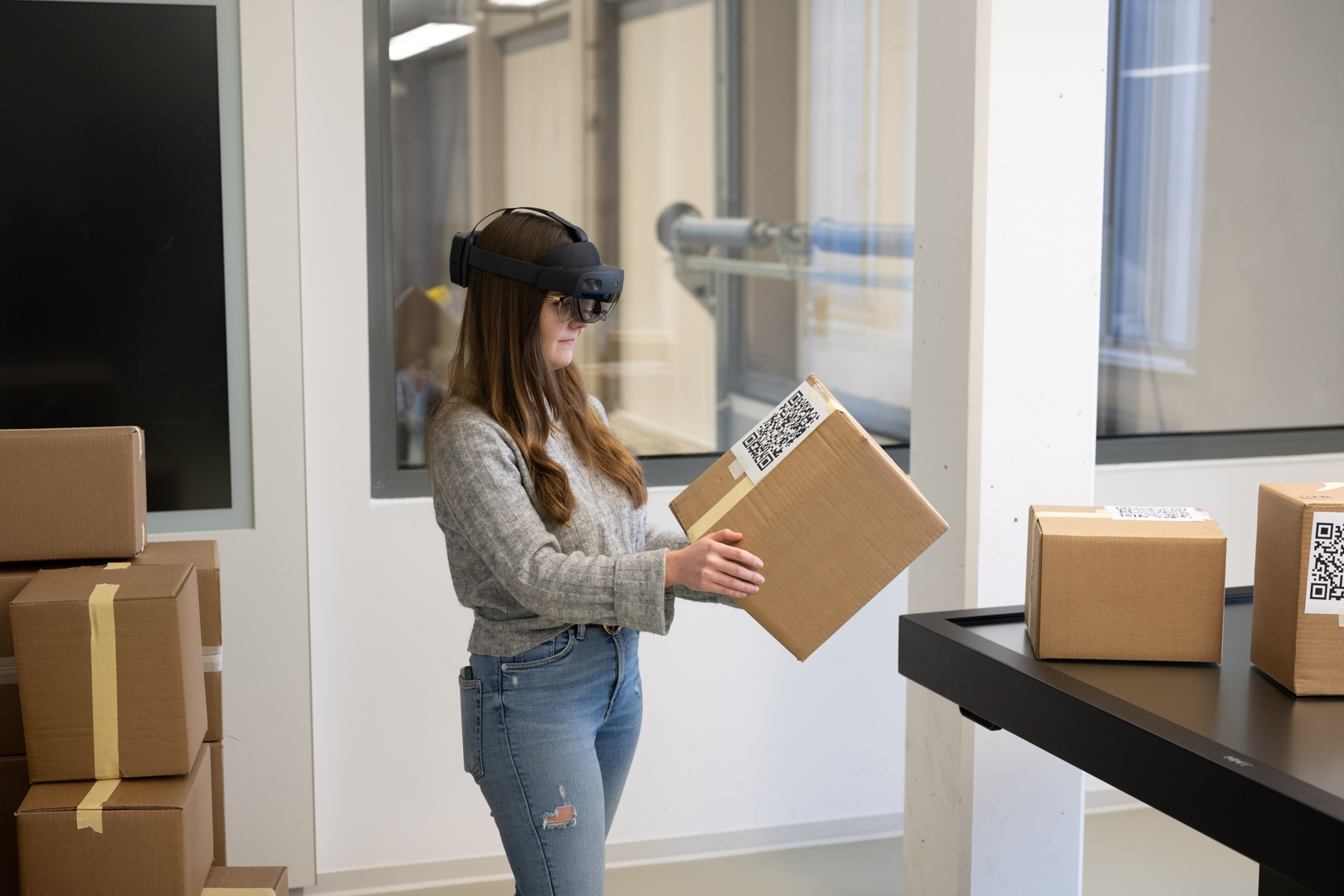 Eine Frau mit einer AR Brille schaut auf ein Paket.