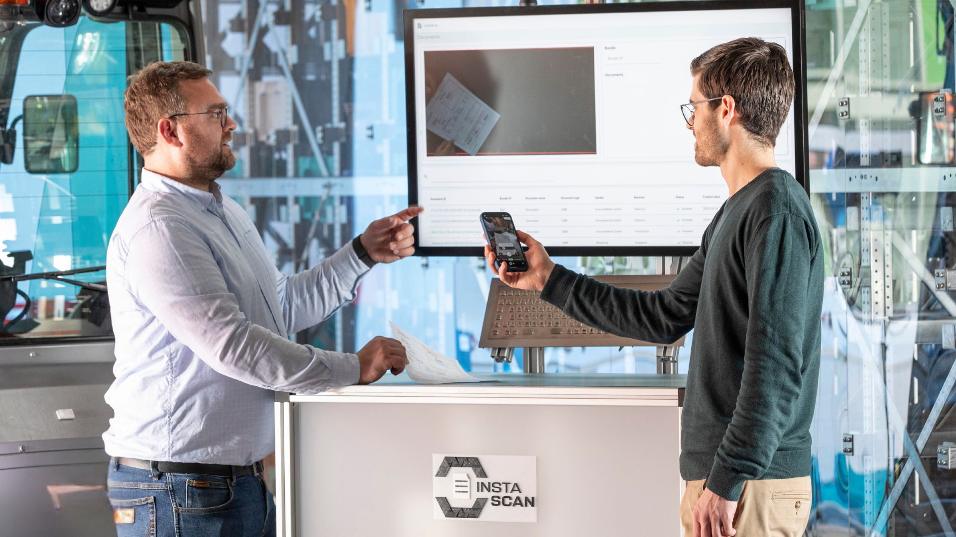 InstaScan – digitalisieren von Dokumenten: Zwei Mitarbeitende scannen einen CMR Frachtbrief am Lagerpult; maschinenlesbare Dokumente für Transportdokumente und Begleitpapiere; digitaler Frachtbrief inklusive.