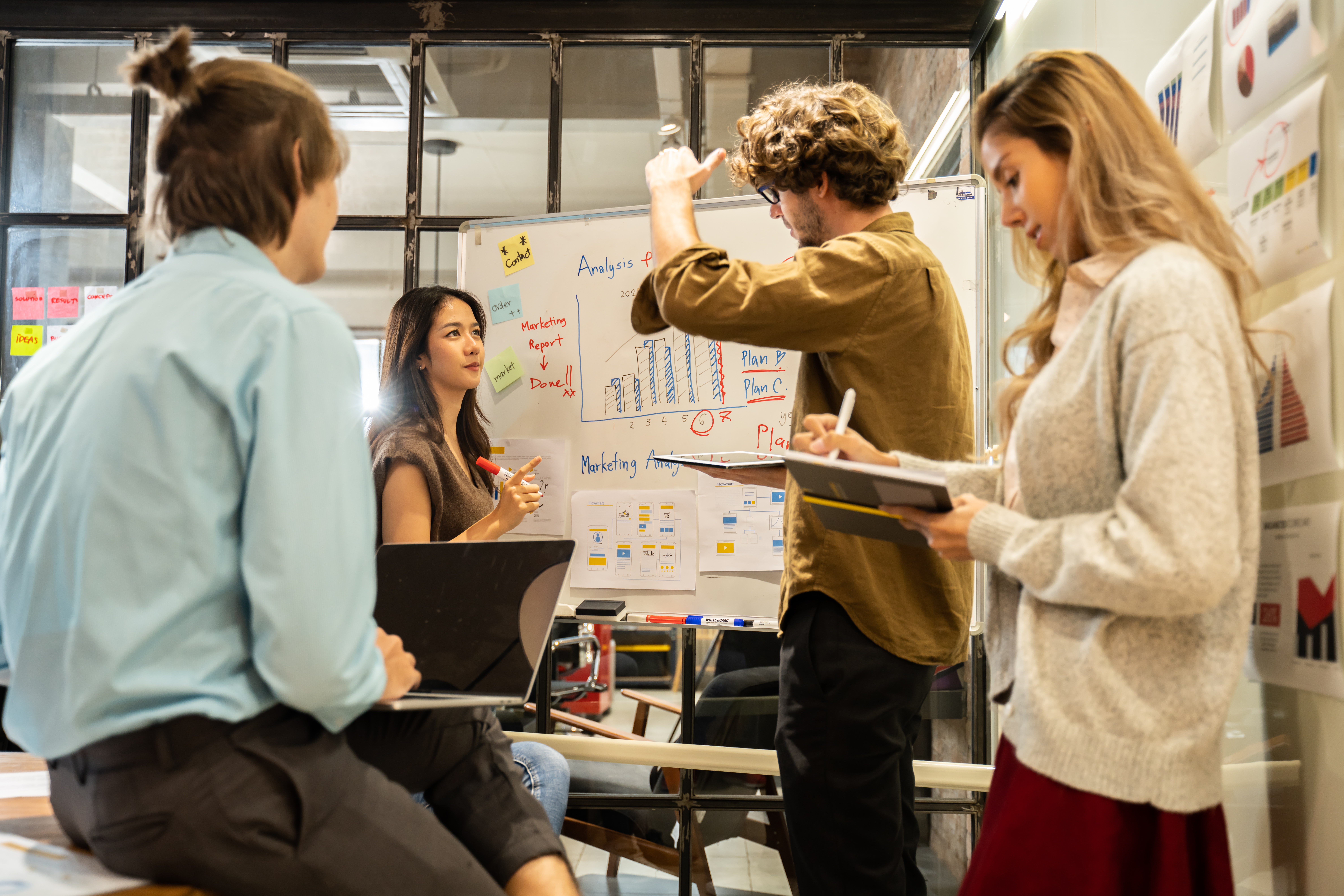 Eine Gruppe junger kreativer Geschäftsleute, die in einer Brainstorming-Sitzung einen Fahrplan für die Produkteinführung, die Planung, die Strategie, die Entwicklung eines neuen Unternehmens und die Arbeit an einem neuen Startup-Projekt im Büro besprechen.