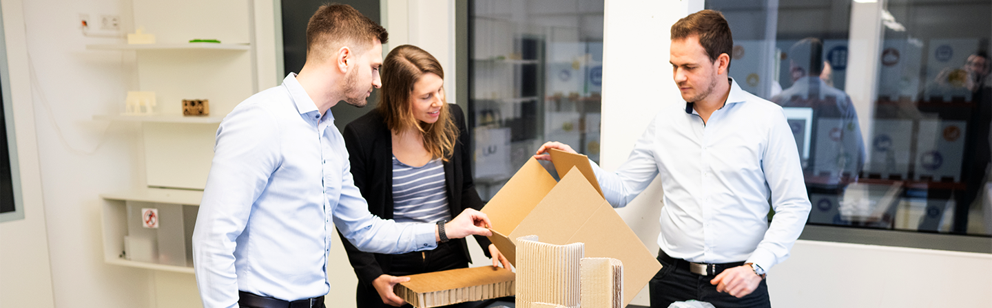 The picture shows three people looking at an environmentally sustainable packaging. As part of the SustainPack project by Fraunhofer IML, packaging systems were assessed ecologically.