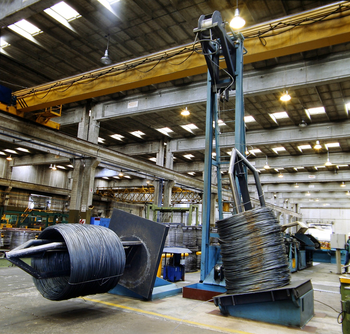 The image depicts a factory environment with heavy machinery for material handling, highlighting the importance of ecological and economic assessment in manufacturing processes.