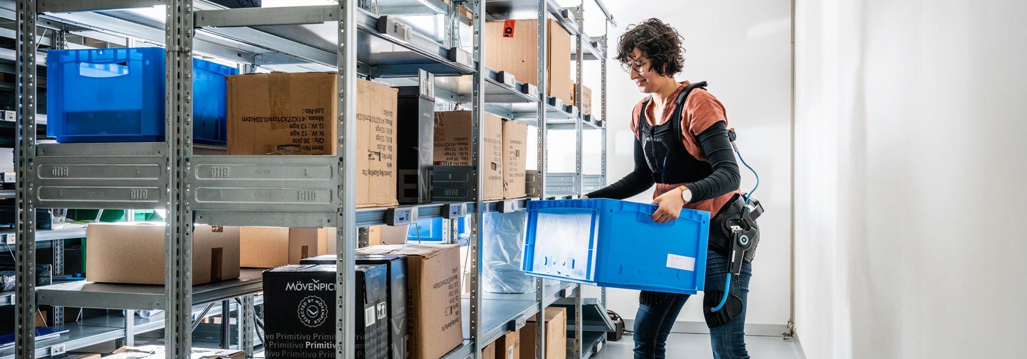 Exoskelett Lab Eine Frau nutzt ein Exoskelett fürs Heben und Tragen von Kisten.