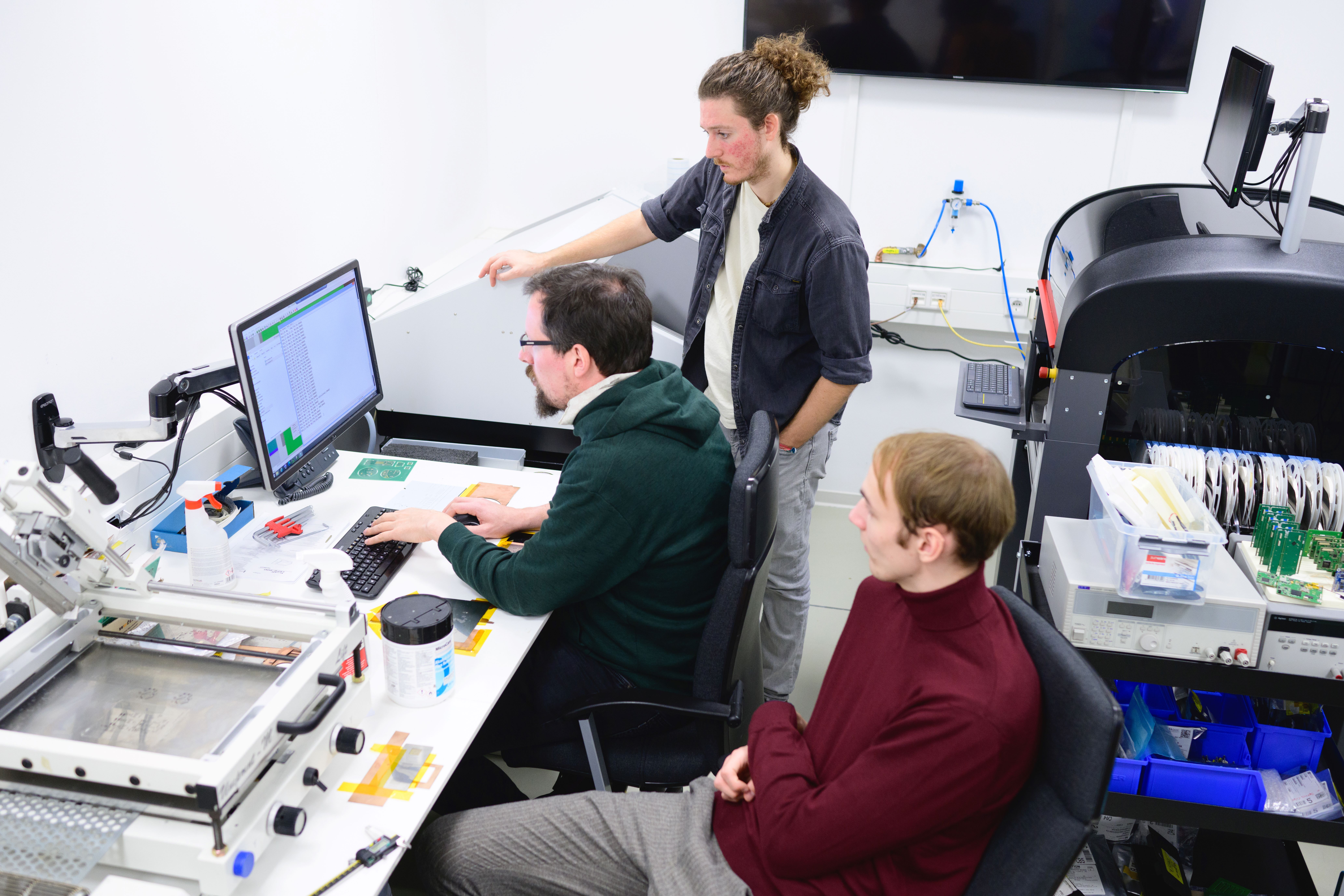 Multiple collegues work together and discuss information on a computer screen