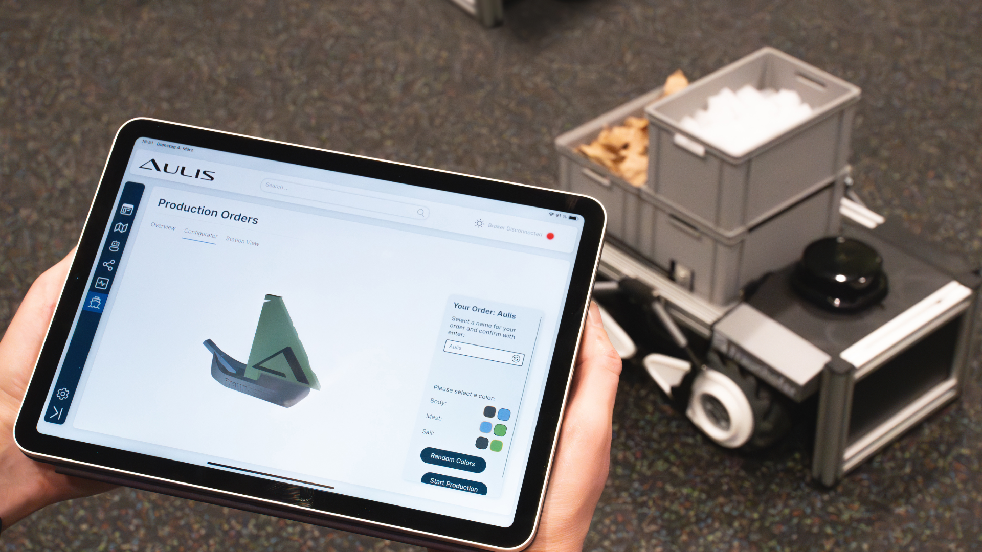 A person holds a tablet in their hand on which Aulis is being used.