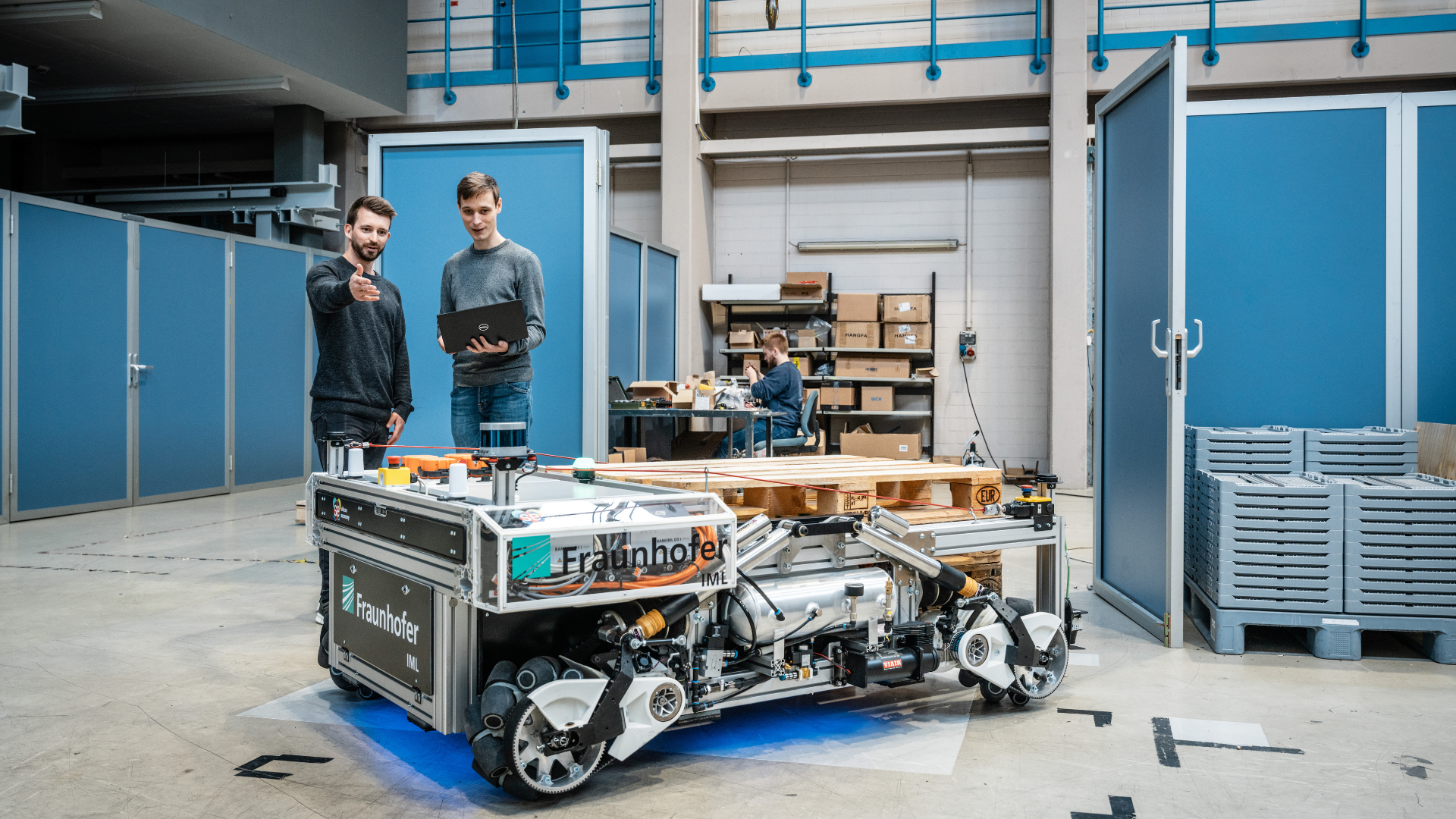 Two researchers are standing next to the transport robot Odyn. 